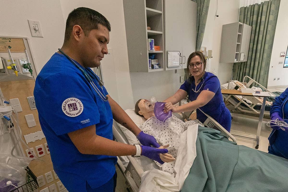 两名圣胡安护理专业的学生示范检查脉搏和给假人吸氧